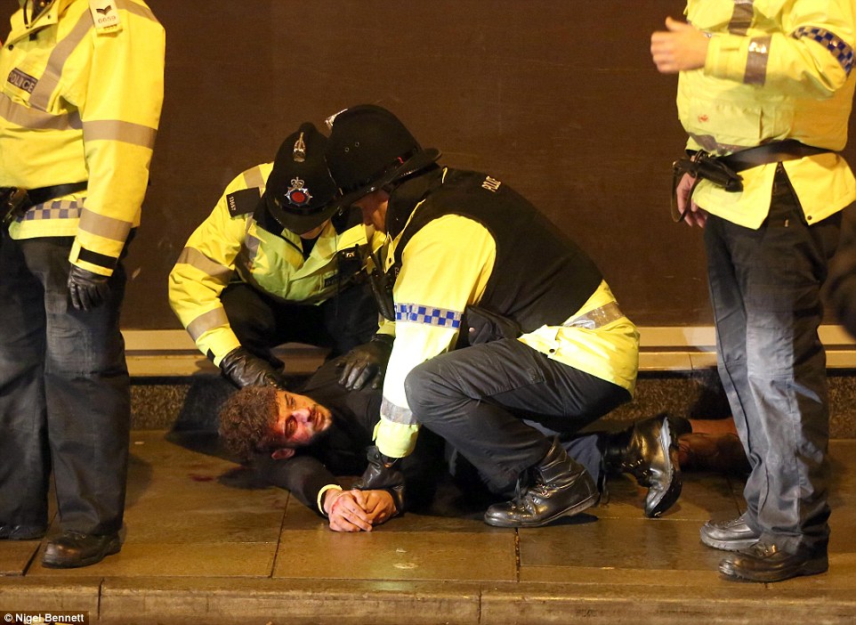 Arrest: A man is held by two police officers on New Year's Eve in Manchester city centre 