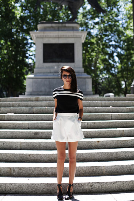 Модель в белых шортах и черной футболке с полосками