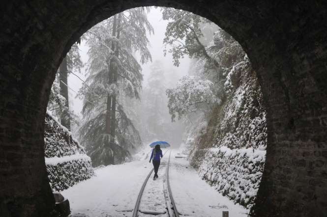 A pedestrian walks along a narrow-gauge railroad track during heavy snowfall in the northern hill town of Shimla on February 15, 2014.