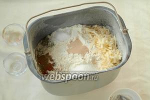 Муку разровнять, по углам всыпать натёртый сыр, сахар, соль, травы, паприку и чесночную приправу. В центр всыпать дрожжи.