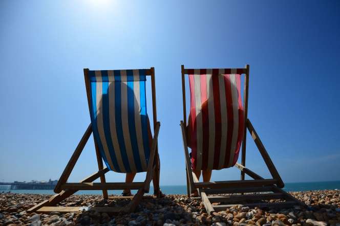 People relax in deck chairs on the beach in Brighton on July 18, 2014, as parts of the country were expected to experience the hottest day of the year so far.