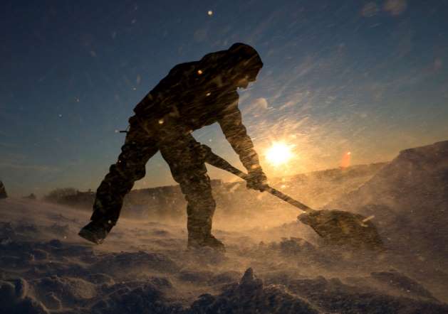 Fierce winds blow snow as snowboarder Garrett Ramos, 20, uses a shovel to build a jump, Friday, Jan. 3, 2014.
