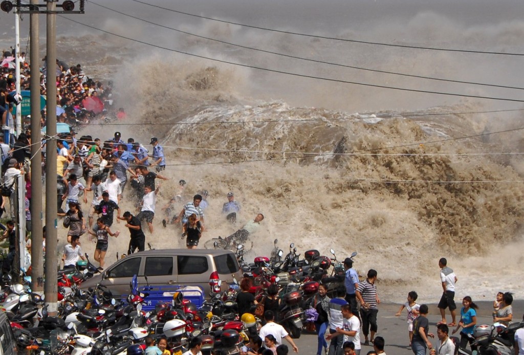 Китайские туристы пытаются убежать от прорвавшей плотину волны на реке Цяньтан. Туристы съезжаются к реке Цяньтан ежегодно, чтобы увидеть самую большую приливную волну в мире. Фото: AFP / East News