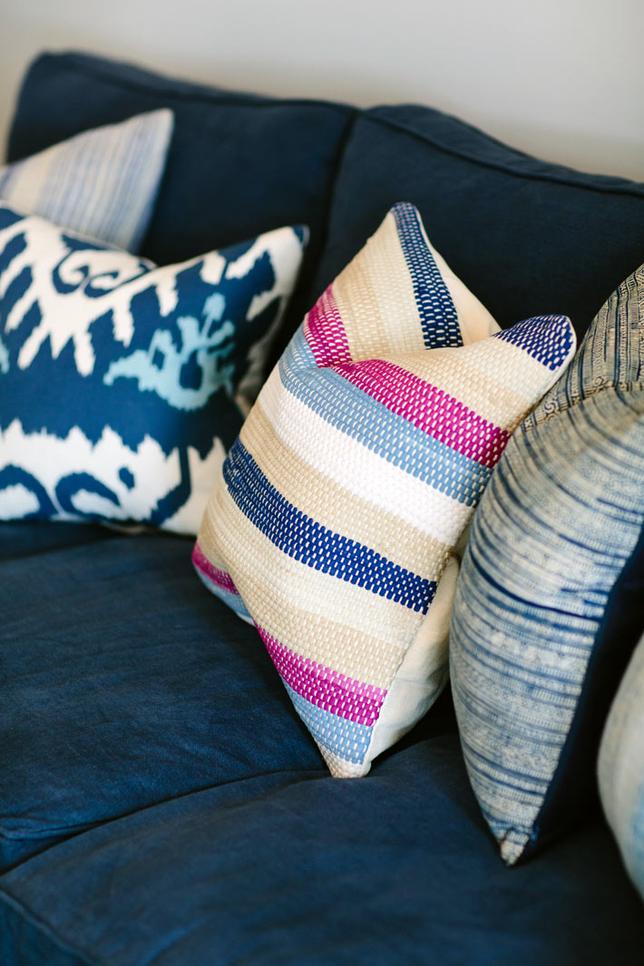 Разные декоративные подушки на фоне синих диванов фото