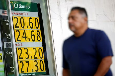 A man walks past a board displaying the exchange rate for Mexican Peso and U.S. Dollar at a currency exchange shop, as the coronavirus disease (COVID-19) outbreak continues, in Mexico City, Mexico March 30, 2020. REUTERS/Gustavo Graf