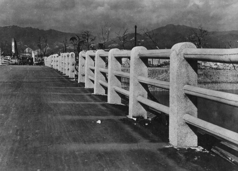 12. Мост через реку Ота в 880 метрах от гипоцентра взрыва над Хиросимой. Заметьте, как сгорела дорога, и слева видны призрачные отпечатки там, где когда-то поверхность защищали бетонные колонны. (U.S. National Archives)