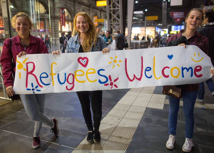 Girls-standing-with-sign-welcoming-migrants-70132.jpg