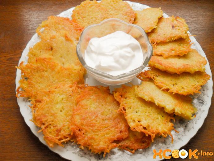драники с чесноком сможет приготовить каждая хозяйка жареные картофельные драники с чесноком со сметаной в соуснице в центре тарелки на столе