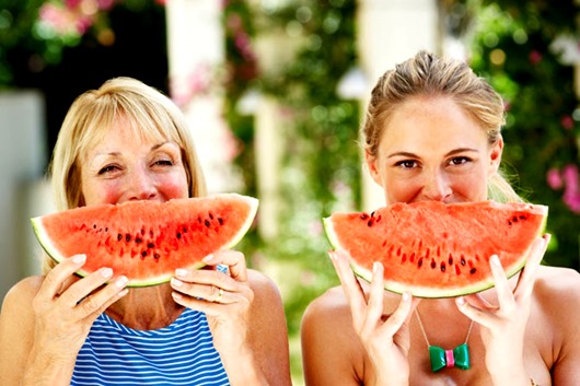 Mother And Adult Daughter Enjoying Slices Of Water Melon