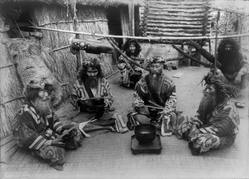 Шесть айнов в традиционных нарядах сидят у чаши. айны, история, народ, фотография