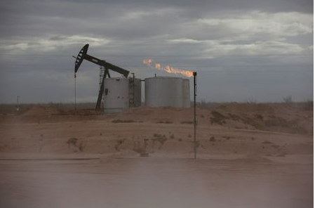 FILE PHOTO: Dust blows around a crude oil pump jack and flare burning excess gas at a drill pad in the Permian Basin in Loving County, Texas, U.S. November 25, 2019. Picture taken November 25, 2019. REUTERS/Angus Mordant/File Photo