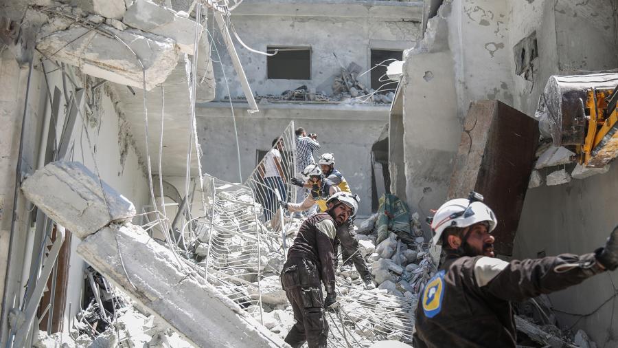 Члены «Сирийской гражданской обороны», также известные как «Белые каски» в руинах разрушенного здания
