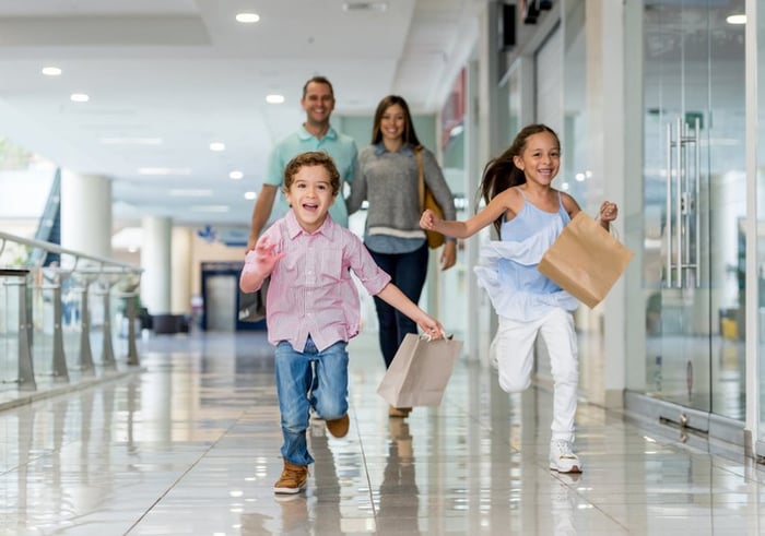 Parents and kids at shopping mall with shopping bags.