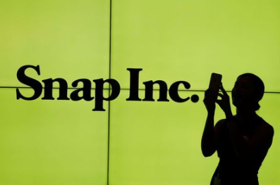 A woman stands in front of the logo of Snap Inc. on the floor of the New York Stock Exchange (NYSE) while waiting for Snap Inc. to post their IPO, in New York City, NY, U.S. March 2, 2017. REUTERS/Lucas Jackson TPX IMAGES OF THE DAY