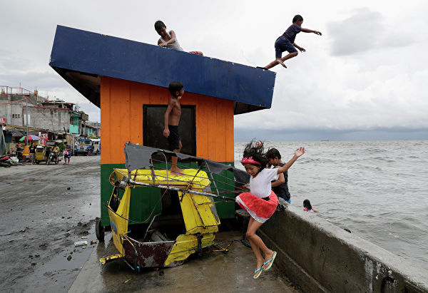 Дети прыгают в воду во время шторма на пляже в Маниле 