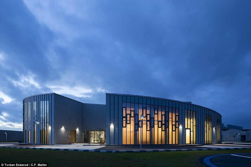 Inmates get a comfortable bed, desk with reading lamp, private bathroom and a share in communal kitchens where prisoners can make their own food. Pictured: The main building at night 