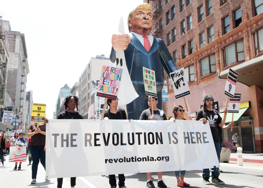 "Революция уже здесь" написано на полотне. И адрес для добровольцев, будущих революционеров. Судя по адресу, в Лос-Анджелесе. 