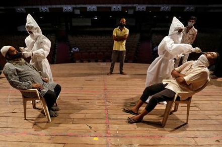 Healthcare workers wearing personal protective equipment (PPE) collect swab samples from men during a rapid antigen testing campaign for the coronavirus disease (COVID-19), at an auditorium turned into a testing centre in Ahmedabad, India, March 23, 2021. REUTERS/Amit Dave
