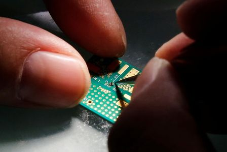 A researcher plants a semiconductor on an interface board during a research work to design and develop a semiconductor product at Tsinghua Unigroup research centre in Beijing, China, February 29, 2016. REUTERS/Kim Kyung-Hoon