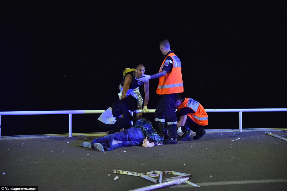 Awful: Friends of a man lying badly injured on the pavement try to treat him as he lies stricken on the floor with no shoes