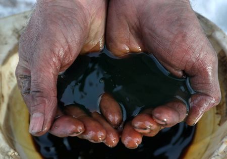 FILE PHOTO: An employee demonstrates a sample of crude oil in the Yarakta Oil Field, owned by Irkutsk Oil Company (INK), in Irkutsk Region, Russia in this picture illustration taken March 11, 2019. REUTERS/Vasily Fedosenko/Illustration/File Photo