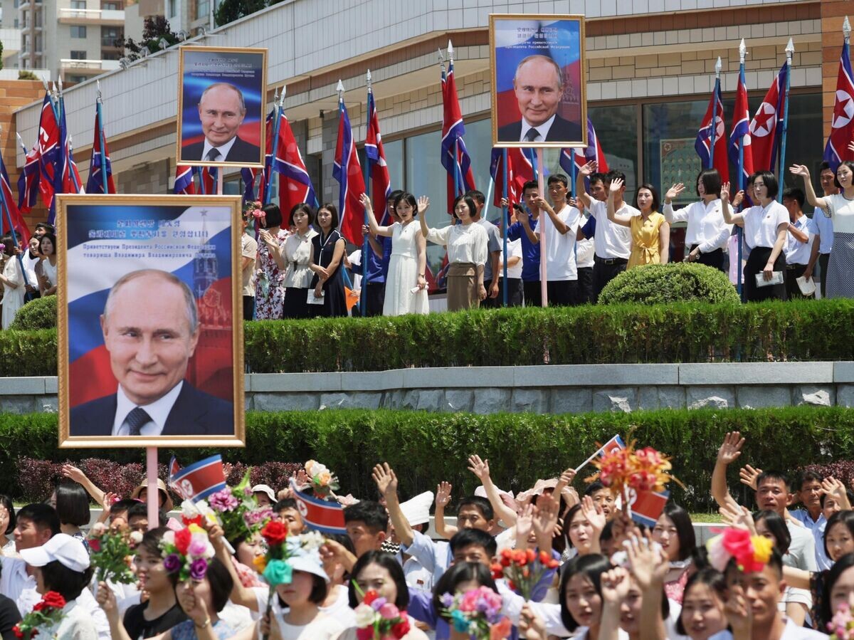    Люди приветствуют кортеж президента РФ Владимира Путина на улице в Пхеньяне© РИА Новости / POOL