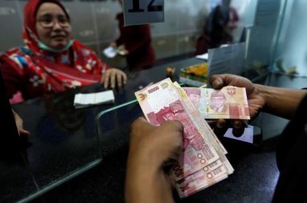 A customer holds Indonesian rupiah bank notes at a money changer in Jakarta, Indonesia August 13, 2018. REUTERS/Willy Kurniawan