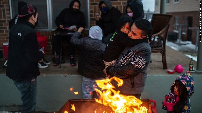  Eric Traugott warms up his young son, Eric Traugott Jr., beside a fire, made from a discarded wooden armoire outside of their apartment in Austin, Texas, that remains without power on Feb. 17, 2021. They’ve been without power since early Monday morning. (Tamir Kalifa/The New York Times)