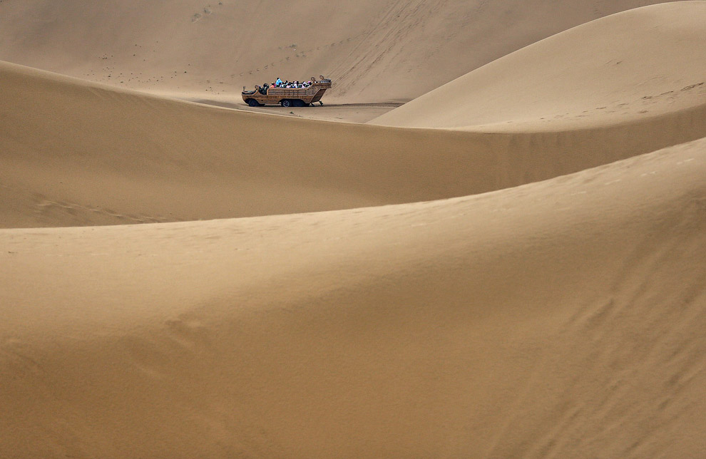 Туристы передвигаются по дюнам в необычных повозках