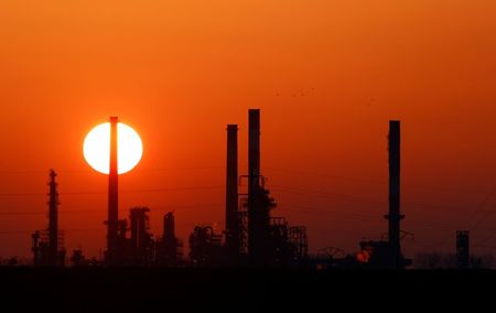 The sun sets behind the chimneys of the Total Grandpuits oil refinery, southeast of Paris, France, March 1, 2021. REUTERS/Christian Hartmann