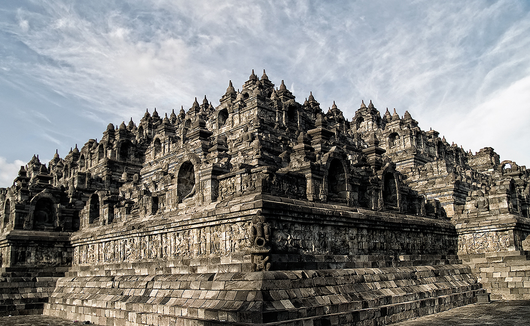 Храм Боробудур Индонезия Весьма примечательный архитектурный комплекс занимает всю вершину довольно высокого холма: храм Боробудур отличается необычной ступенчатой структурой невероятно искусной росписью по камню &mdash; ею покрыты многие стены и ступени постройки.
