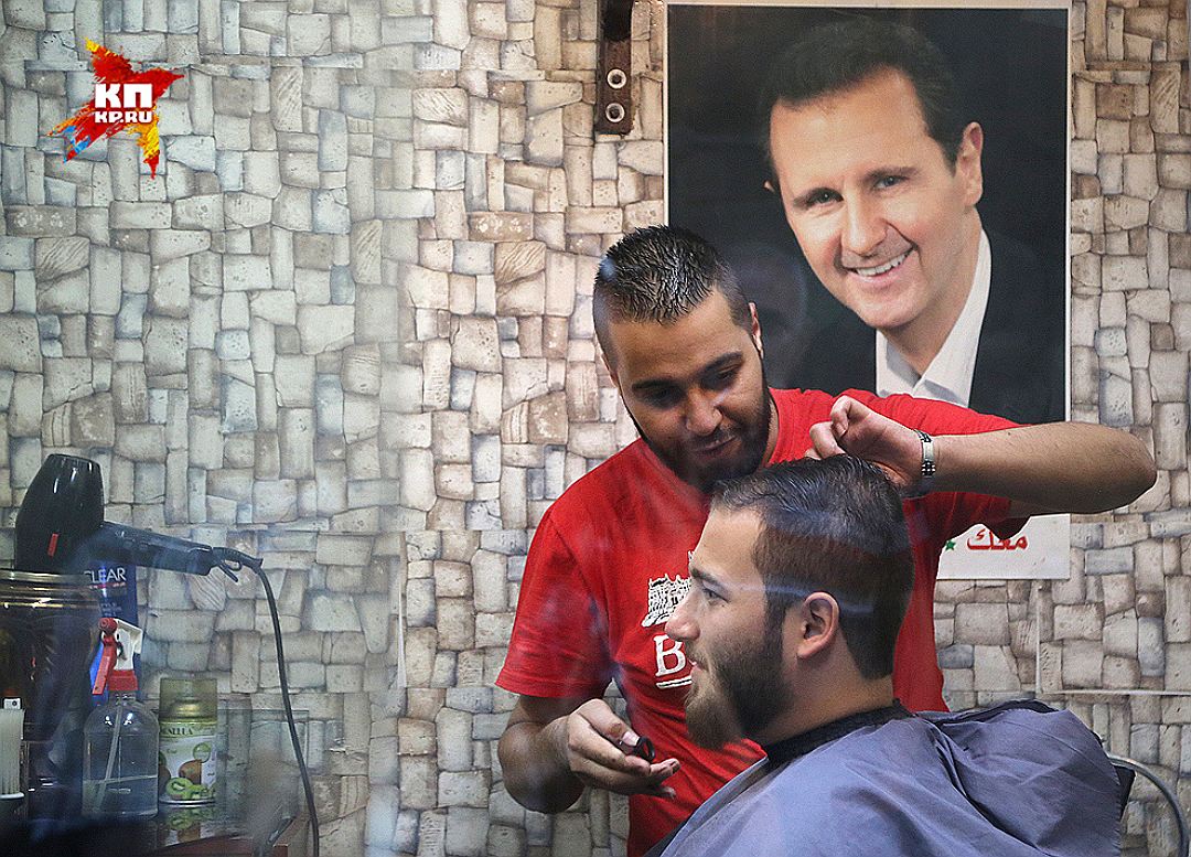 Дамаск. Парикмахер стрижет мужчину в салоне. На стене - портрет президента Сирии Башара Асада. Фото: Александр КОЦ