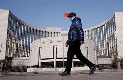 A man wearing a mask walks past the headquarters of the People's Bank of China, the central bank, in Beijing, China, as the country is hit by an outbreak of the new coronavirus, February 3, 2020. REUTERS/Jason Lee