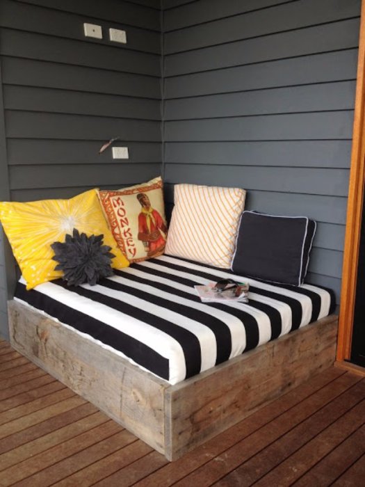 Удобный и стильный диванчик на крыльце с деревянным основанием, который позволит отдохнуть на свежем воздухе.