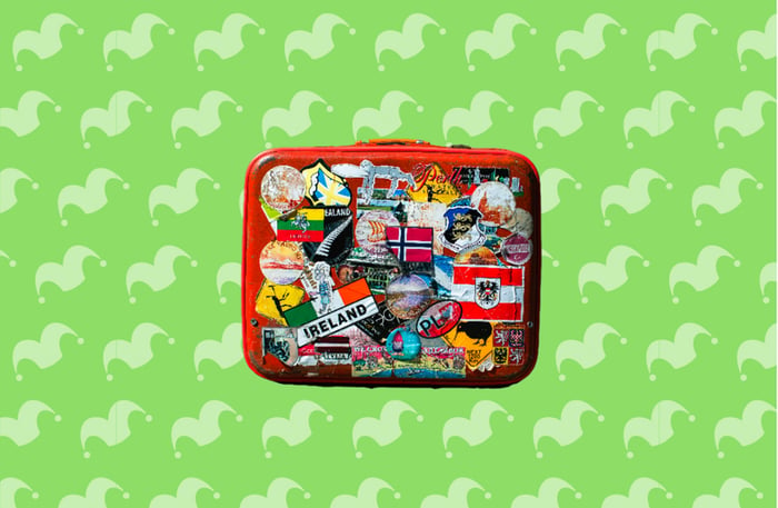 A suitcase covered in stickers against a green background