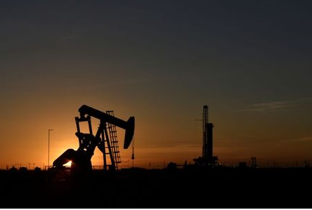 A pump jack operates in front of a drilling rig at sunset in an oil field in Midland, Texas U.S. August 22, 2018. Picture taken August 22, 2018. REUTERS/Nick Oxford