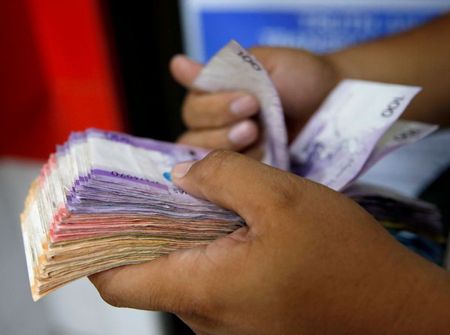 FILE PHOTO: A man counts a wad of Philippine Peso bills he received from a relative working abroad at a money remittance center in Makati City, Metro Manila, Philippines September 19, 2018. REUTERS/Eloisa Lopez/File Photo