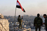 A Syrian government soldier gestures a v-sign under the Syrian national flag near a general view of eastern Aleppo after they took control of al-Sakhour neigbourhood in Aleppo, Syria in this handout picture provided by SANA on November 28, 2016. SANA/Handout via REUTERS ATTENTION EDITORS - THIS IMAGE WAS PROVIDED BY A THIRD PARTY. EDITORIAL USE ONLY. REUTERS IS UNABLE TO INDEPENDENTLY VERIFY THIS IMAGE. - RTSTSGY