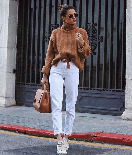 Девушка в прямых белых джинсах, коричневый свитер и кроссовки