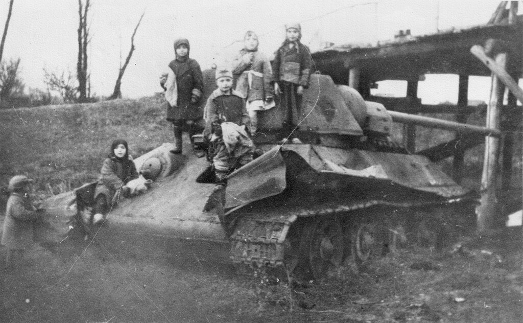 Дети на брошенном у моста советском танке Т-34-76. Фото не ранее осени 1942 года, так как танк оснащен башней-