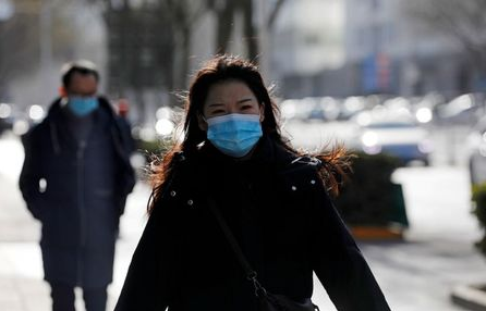 A woman wearing a face mask walks along a street, following new cases of the coronavirus disease (COVID-19) in the country, in Beijing, China January 11, 2021. REUTERS/Tingshu Wang