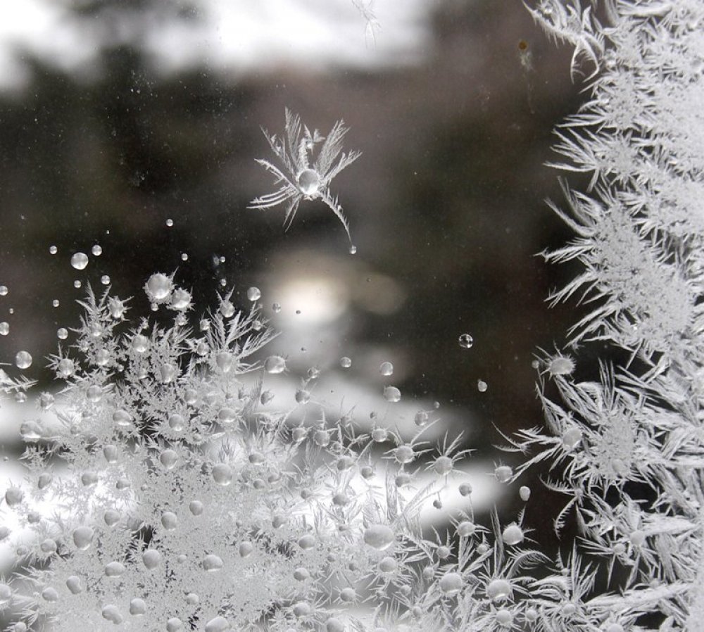 В воздухе кружатся пушистые снежинки. Морозные узоры. Морозные узоры на стекле. Снежные узоры на окнах. Морозные узоры на окне.