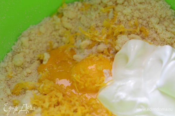 К крошке добавить желтки, ванильный сахар, сметану, цедру лимона и быстро замесить тесто, чтобы не приставало к рукам.