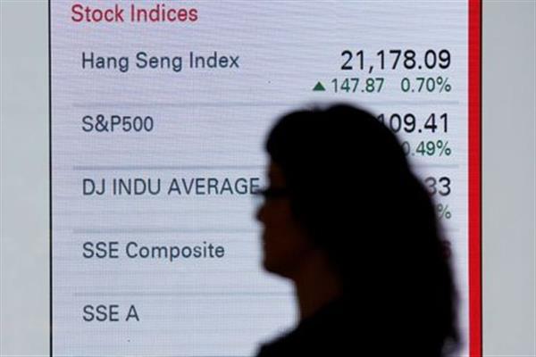 FILE PHOTO: A woman walks past a panel displaying stock indices of Hong Kong, U.S. and China markets, outside a bank in Hong Kong June 7, 2016. To match Analysis CHINA-HONGKONGSHENZHEN/MSCI REUTERS/Bobby Yip//File Photo 