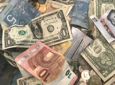 U.S. dollars and other world currencies lie in a charity receptacle at Pearson international airport in Toronto, Ontario, Canada June 13, 2018. REUTERS/Chris Helgren