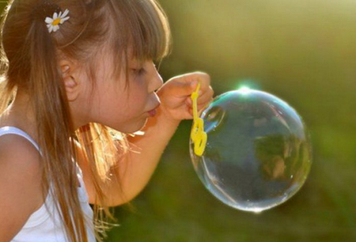 девочка надувает мыльный пузырь
