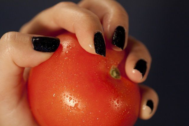 View of a woman hands holding a red tomatoe.