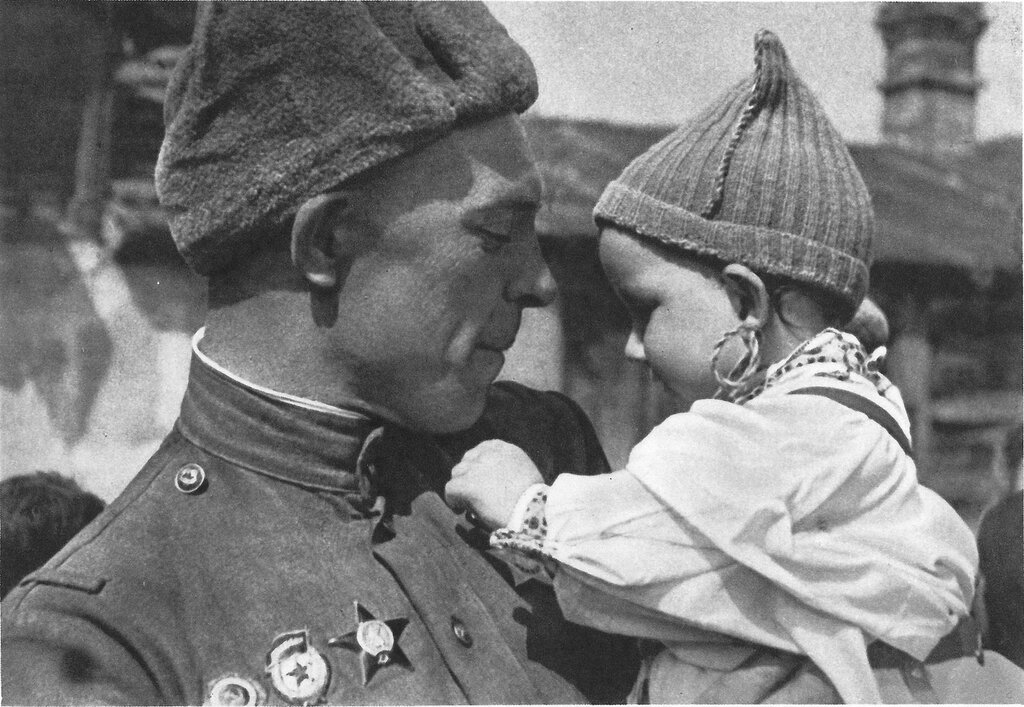 Советский солдат с чешским ребенком на руках. Малыш рассматривает орден Славы на груди бойца.Прага, Чехословакия. Май 1945