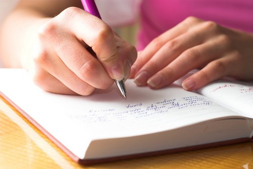 Young female is writing notes and planning her schedule.