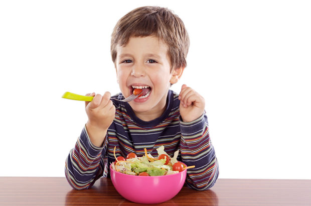 Child eating salad a over white background